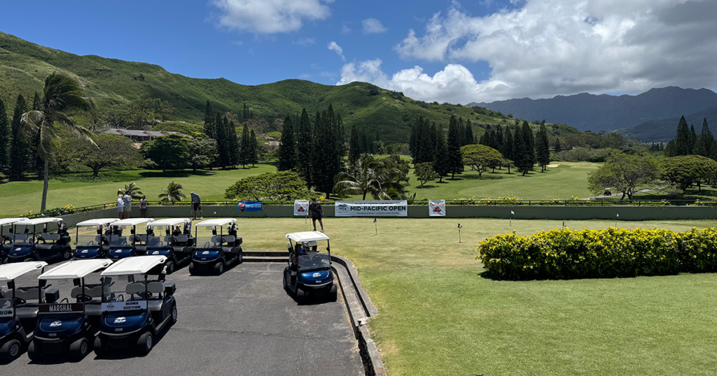View of golf carts lined up for the tournament, with the Mid-Pacific Open banner visible