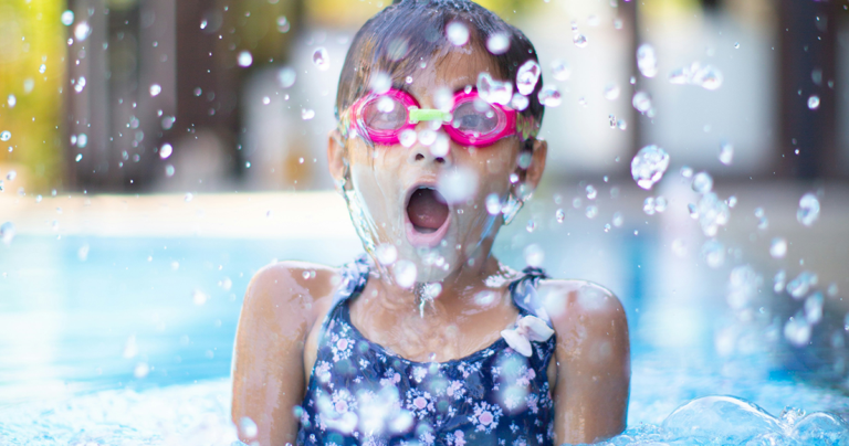 A girl coming up for air with joy during swim lessons