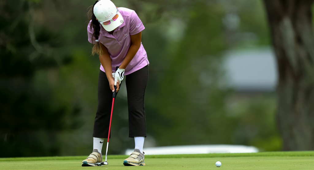 A woman golfer practicing her short game on the putting green at Mid-Pacific Golf Club